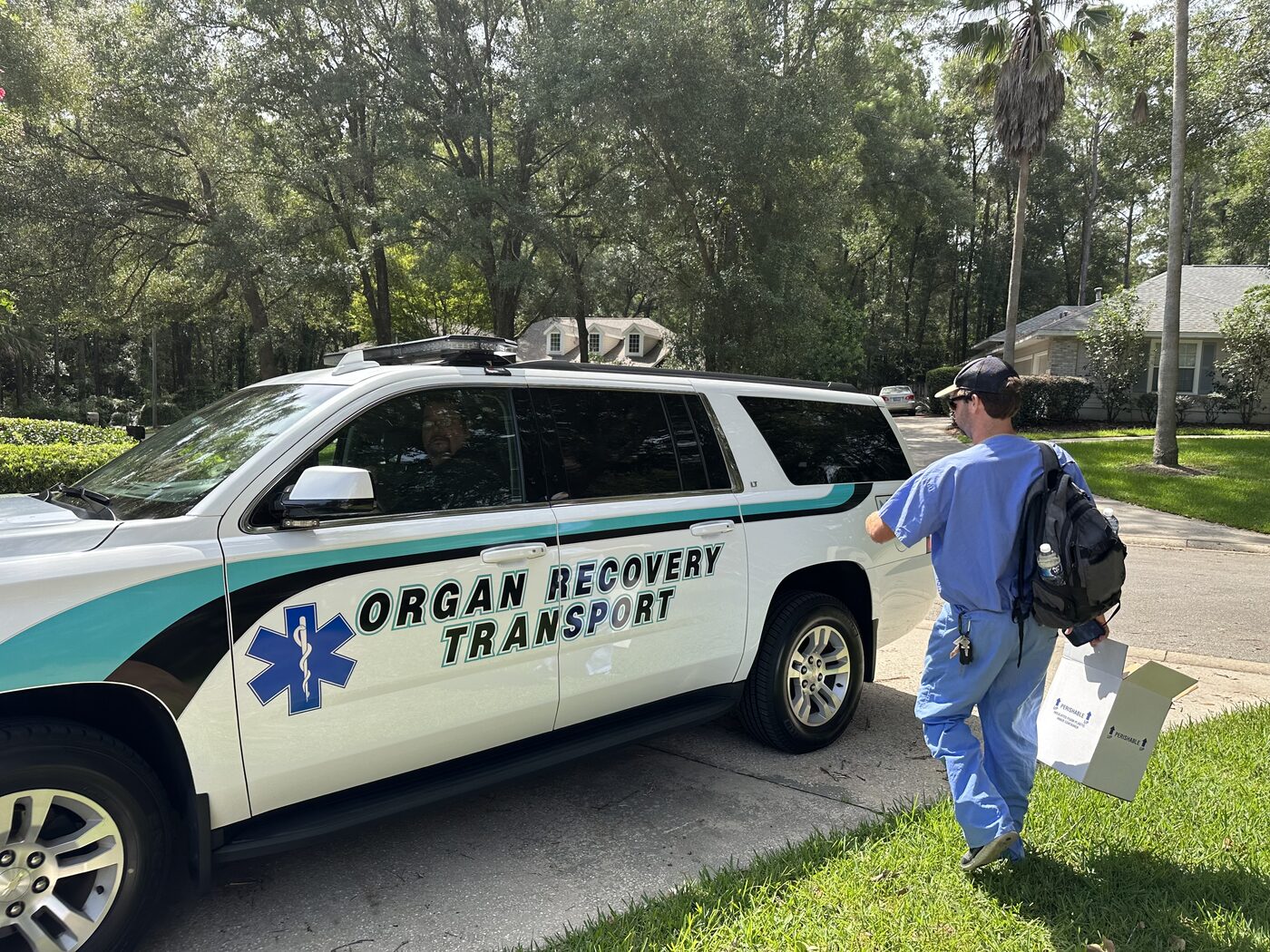 Sam in scrubs walking to an Organ Recovery Transport vehicle